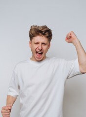 Young man celebrates victory with a raised fist and an excited expression indoors
