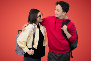 friendly students pose with backpacks pose together against bright red background in casual youthful portrait
