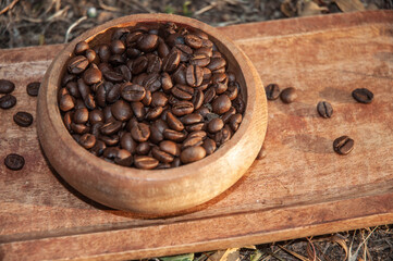 Coffee beans in a wooden bowl on wooden tray. No people