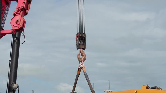 Crane is lifting the heavy object using main hook and web sling equipment. Industrial operation, close-up at the object. 