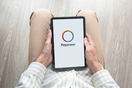 03.03.2025, Batumi, Georgia: Person holding tablet with Payoneer logo on screen, symbolizing online payments, finance technology, remote work, and digital banking services