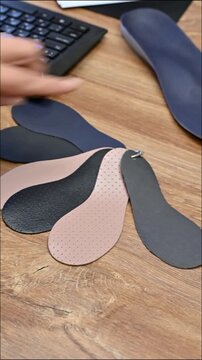 Different types of shoe insoles laid out on a wooden table for comparison and selection