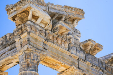 Intricate Architectural Details of Ancient Columns Showcasing Sculpted Figures Against a Clear Blue Sky