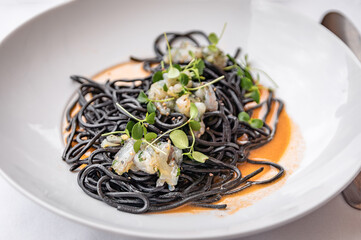 Pasta nero di sepia with squid ink and raw shrimp at a restaurant, Nice, France