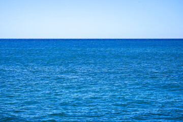 An Expansive View of Calm Blue Ocean Water Under a Clear Blue Sky with Gentle Waves Lapping at the Surface, Reflecting Sunshine and Serenity