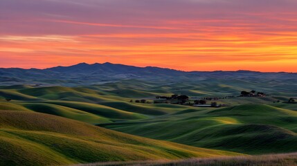 Obraz premium Rolling green hills meet a vibrant sunrise over distant mountains.