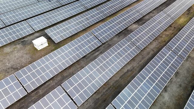 Aerial view of a solar farm with rows of photovoltaic panels, symbolizing renewable energy and environmental protection.