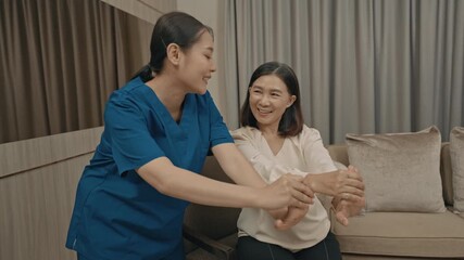 asian female caregiver assisting senior woman with physical therapy exercise at home during rehabilitation process to improve mobility strength and overall health care support in daily life