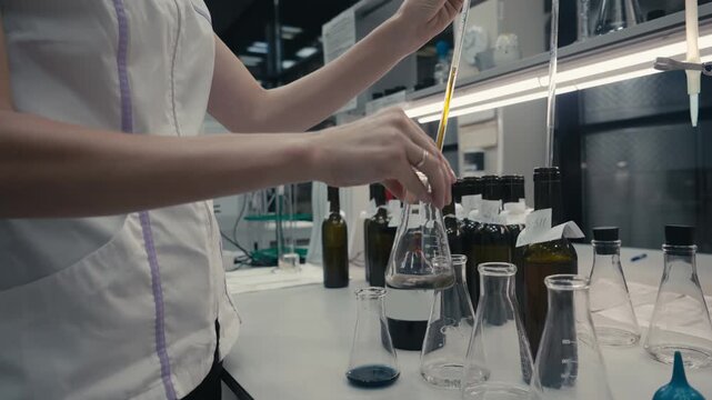 Shaking the glass flask with chemical liquid on the bottom. Chemical liquid inside the small flask changing colour from brown to black. Chemical reaction with the liquid in the flask at the laboratory