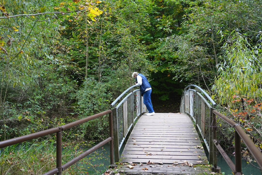 Eine Frau steht auf einer Br&uuml;cke und schaut  auf die Rhumequelle - eine Karstquelle - im Landkreis G&ouml;ttingen bei Rhumspringe in Niedersachsen in Deutschland	