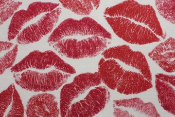 Red lipstick kiss marks creating a seamless background pattern on white