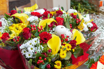 Festive bouquet of red, yellow, white Christmas flowers with candle and berries on sale at Rialto Market, Venice, Veneto, Italy