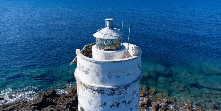 Aerial view of the historic Mangiabarche Lighthouse surrounded by turquoise sea and rocky coast