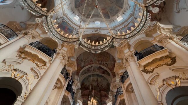Exterior and interior views of the monumental St. Nicholas Church in Prague. Baroque dome frescoes, massive chandeliers, and intricate gilded stucco contrast with the passing city tram.