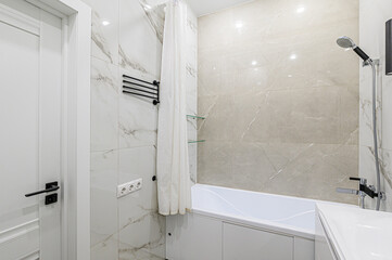 Modern bathroom features marble-like tiles, white bathtub, shower, white curtain, and black hardware. A sleek and clean design with a touch of elegance