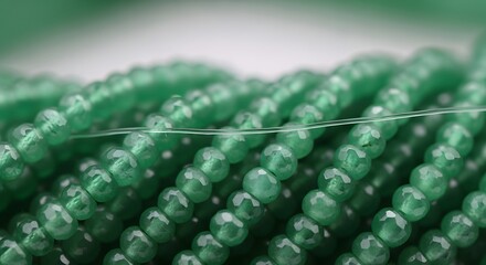 Sparkling emerald green gemstone beads strung on fine thread, perfect for elegant jewelry designs and crafting projects