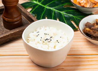 A culinary delight! A bowl of rice, adorned with black sesame seeds, paired with traditional Asian dishes, offering a flavorful and authentic dining experience. Perfect for food blogs.