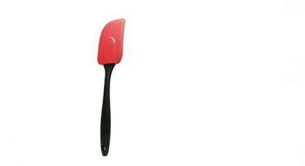A vibrant red rubber spatula with black handle lies on a solid black backdrop in sharp studio light