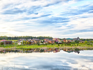 Peaceful village reflected in calm waters during a serene sunset by the lake's edge