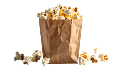 A brown paper bag overflowing with fluffy, buttery popcorn, some spilled around base