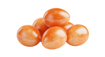 Pile of smooth, orange-colored candies with a glossy finish and small speckles, isolated on black