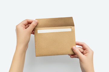 Hands opening a brown kraft paper envelope with a blank white card inside