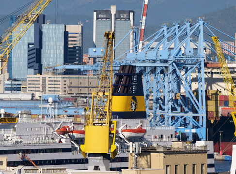 Genoa, Italy - October 2025: ferry ship of the Corsica Ferries company in the shipyard. In the background, port cranes of the Sech terminal and the skyscrapers with the Erg and WTC signs. 