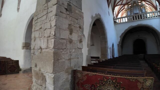 Prejmer Fortified Church interior in Transylvania, Romania, displaying its historic altar, ornate baptismal font, and religious furnishings. UNESCO site of Romania