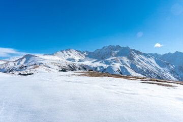 Fototapeta premium Snow-covered mountain peaks near the top ski lift station of Karakol ski resort in the Tian Shan mountains of Kyrgyzstan.