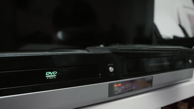 Woman puts a dvd disc into media player.