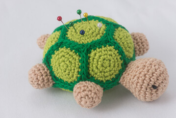 Crochet turtle pincushion with colorful pins, perfect for sewing space