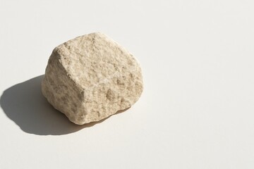Fototapeta premium Beige limestone rock with soft edges and subtle texture, photographed in natural sunlight against a clean neutral background, emphasizing its mineral surface and organic geometry in minimalist style