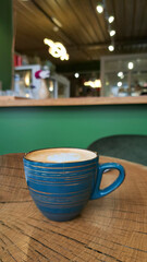 A cup of coffee with milk or cappuccino on a wooden table against the background of a modern cafe