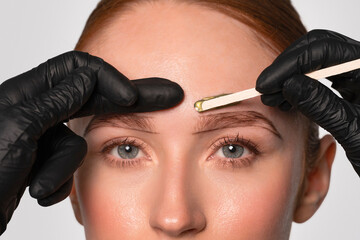 Gentle eyebrow waxing process with skilled hands in a well-lit salon setting