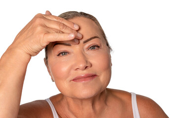 Senior woman applying skincare to her forehead, enjoying self-care routine in a bright, cheerful atmosphere