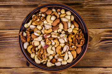 Various nuts (almond, cashew, hazelnut, pistachio, walnut) in ceramic plate on a wooden table. Vegetarian meal. Healthy eating concept. Top view