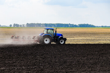 Tractor plowing field with the harrow. Agricultural concept