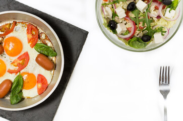 Fried eggs with sausages. Fresh salad and scrambled eggs. Healthy breakfast.