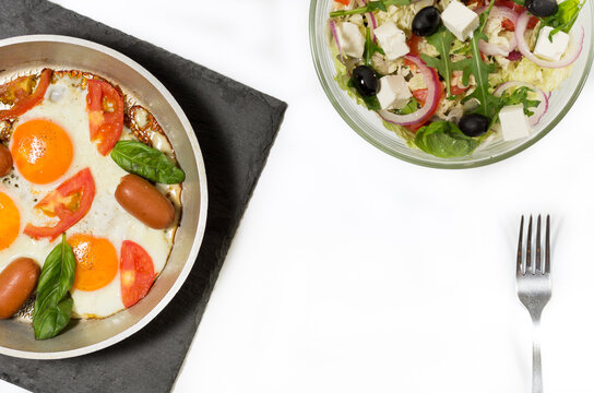 Fried eggs with sausages. Fresh salad and scrambled eggs. Healthy breakfast.