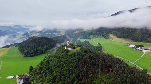 Church of Saint Verena above a foggy valley with scattered farm plots, aerial view
