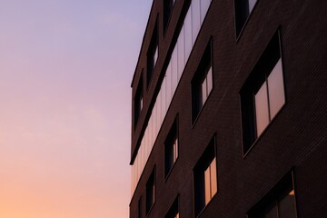 A modern urban building showcases vibrant reflections of a colorful sunset sky during a serene evening moment.