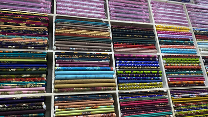 Assortment of colorful fabrics stacked on shelves in a textile store
