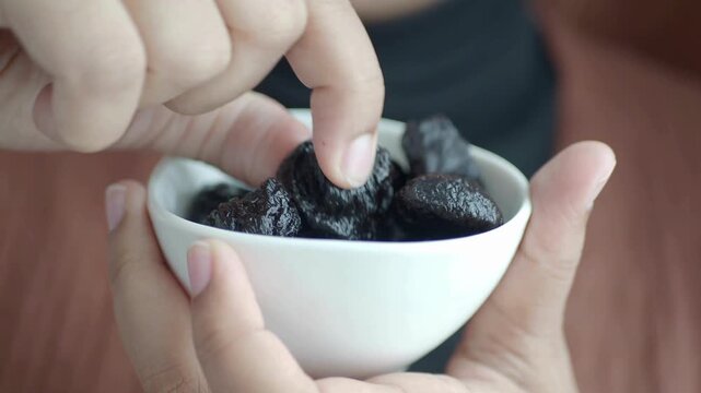 Close Up of Woman Eating Healthy Natural Dried Plums (Prunes) &ndash; Nutrition, Wellness, and Healthy Lifestyle Food Concept in 4K Ultra HD
