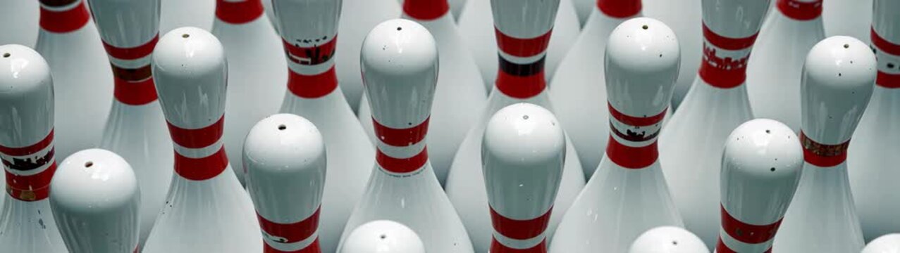 White bowling pins with red stripes standing in neat rows, ready for sport.