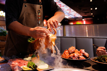 A chef wows diners with a stunning seafood display using dry ice, blending artistry and flavor in a lively eatery.