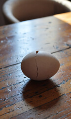solitary cracked easter egg lies worn wooden table surrounded soft natural light subtle