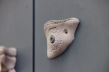 A climbing hold is securely attached to a grey wall, designed for training and bouldering activities.