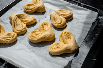 Raw buns on a baking tray with parchment paper