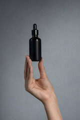 A woman's hand holding a bottle of cosmetics