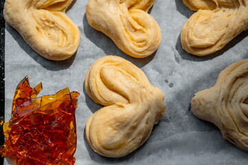 Raw buns on a baking tray with brown caramel sheet, high-sugar and carbohydrate food